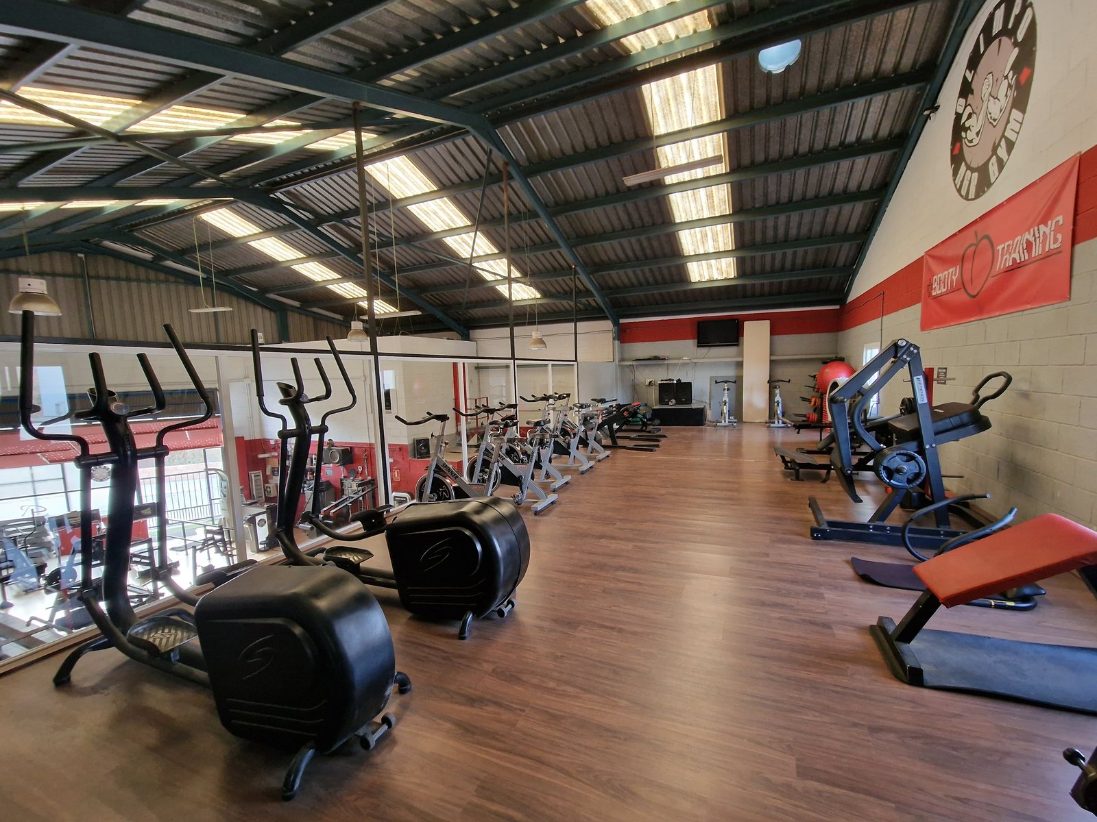 Interior del gimnasio Olimpo NGR con máquinas de cardio y otras máquinas de ejercicio dispuestas en una sala amplia y bien iluminada.